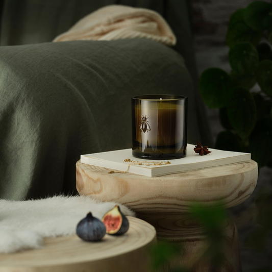 Cozy living room home decor scene with the La Rochere Fig bee candle glowing on a side table next to a comfortable sofa