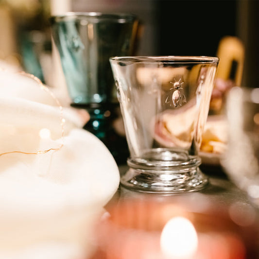 Close up of a clear La Rochère Bee water glass 250ml on a dining table highlighting the embossed bee motif