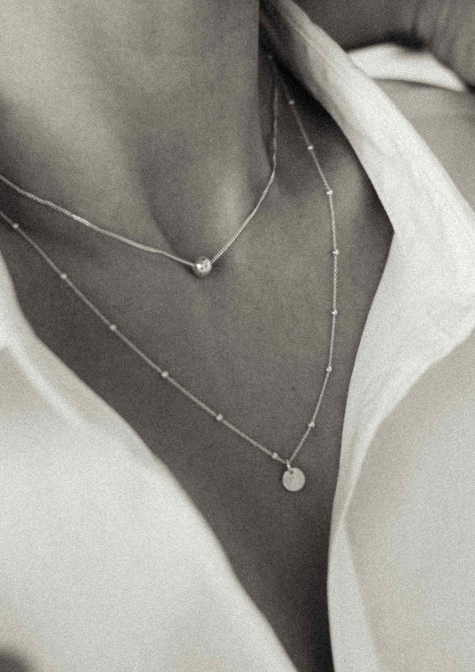 Close-up of a model's neck showcasing the gold Bubble Necklace gracefully layered.