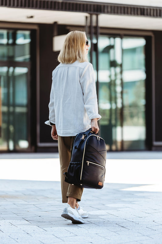 Model holding the Large Espresso Backpack by the top handle