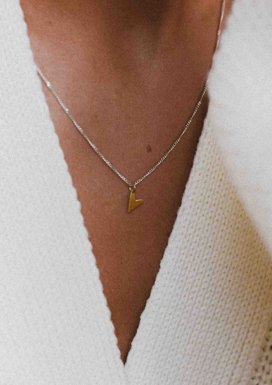 Close-up of a woman wearing the gold Love Necklace resting on her chest.