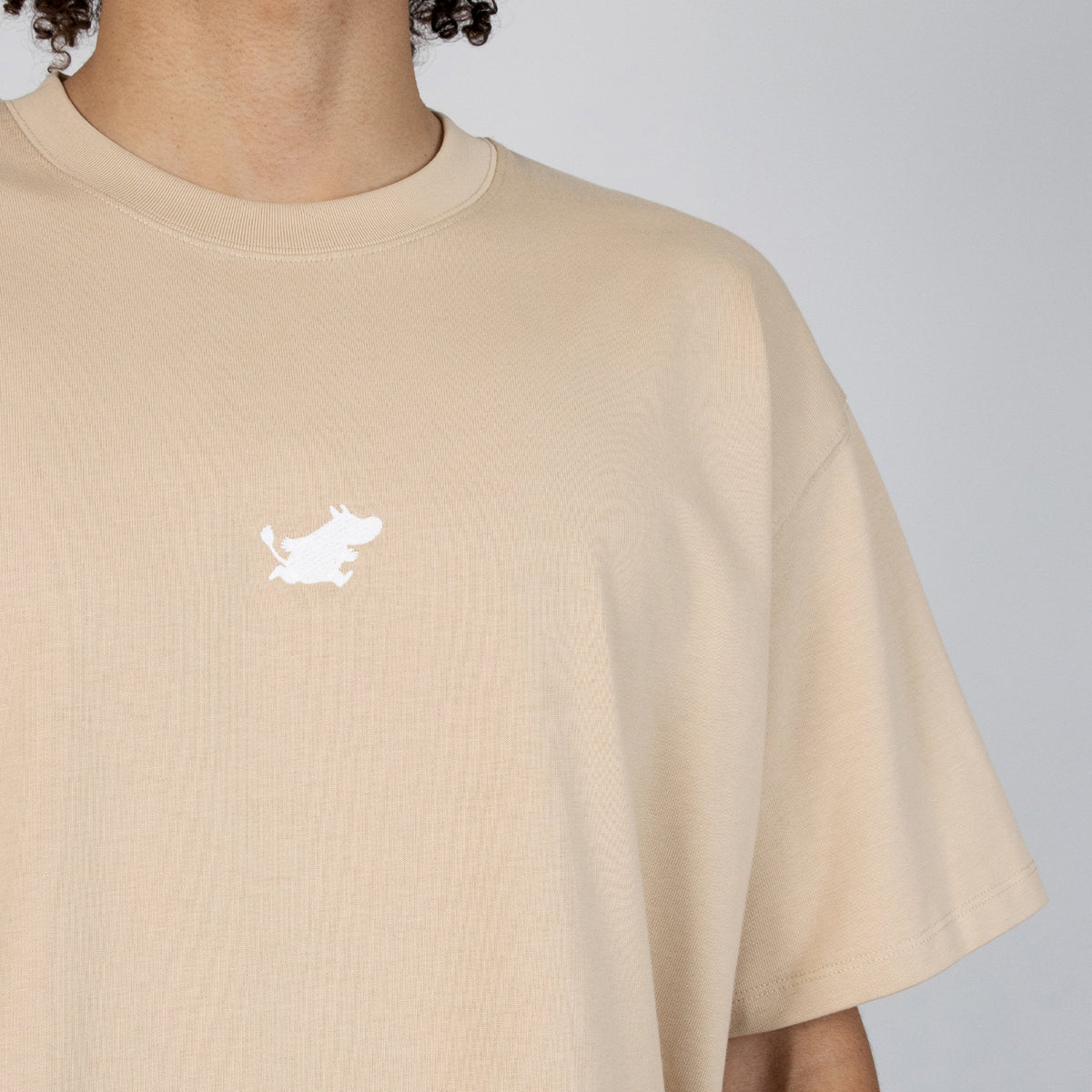 Close-up of Male model wearing the unisex Moomin Classics Heavy T-Shirt Beige.