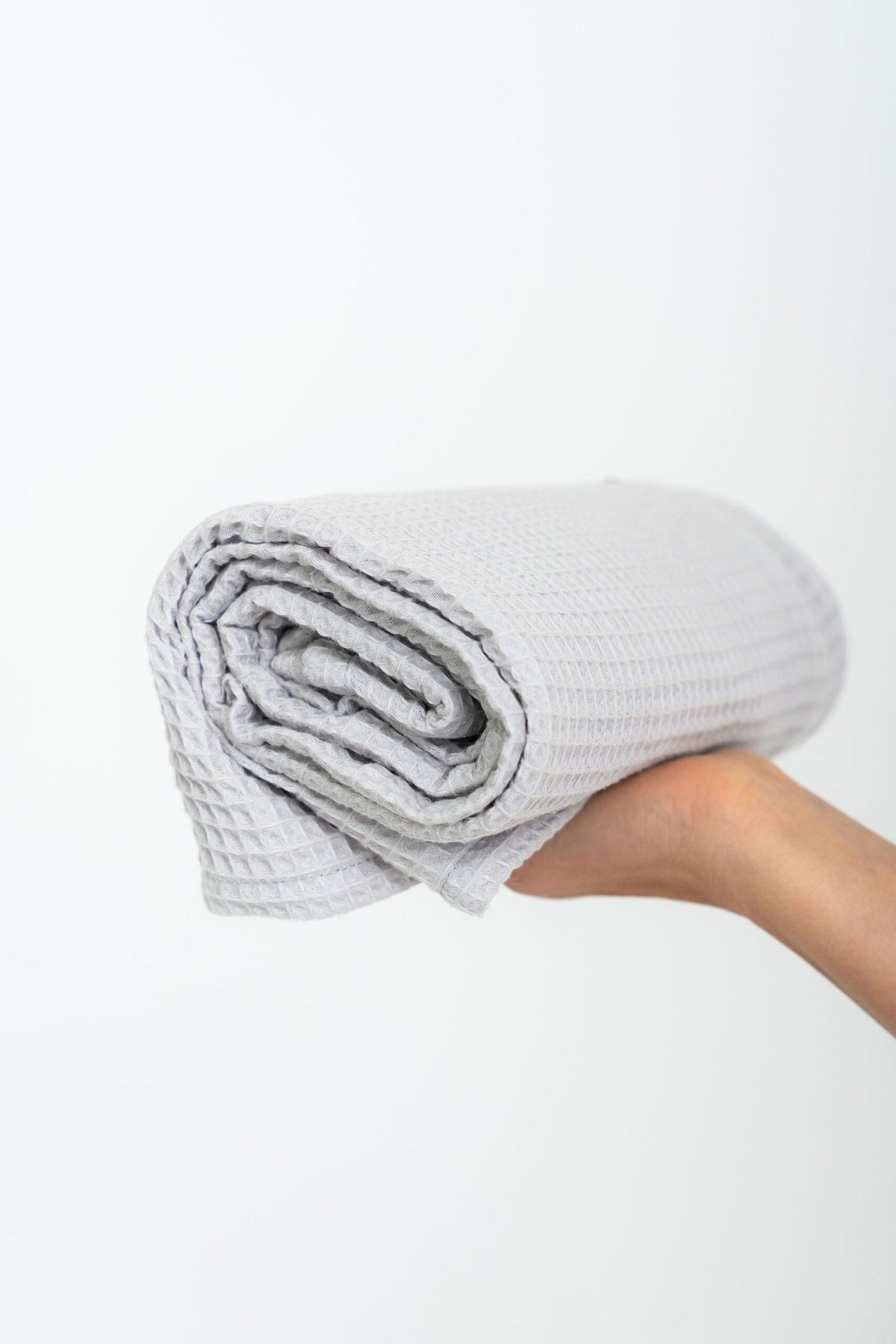 Woman Holding Rolled Light Gray Organic Waffle Cotton Towel | NUSS