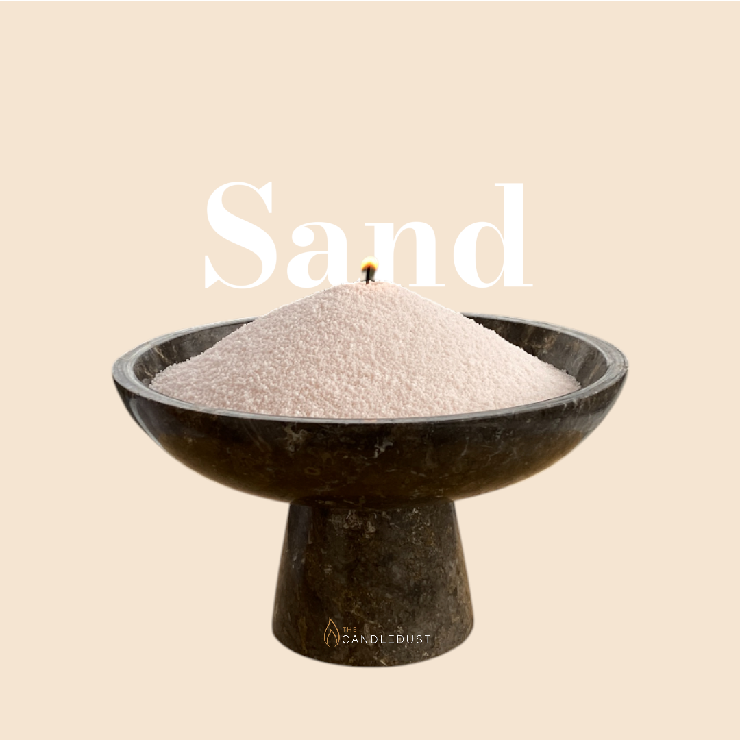 Sand text on a matching warm sand background with a glass vase full of unlit pearled candle sand in the foreground
