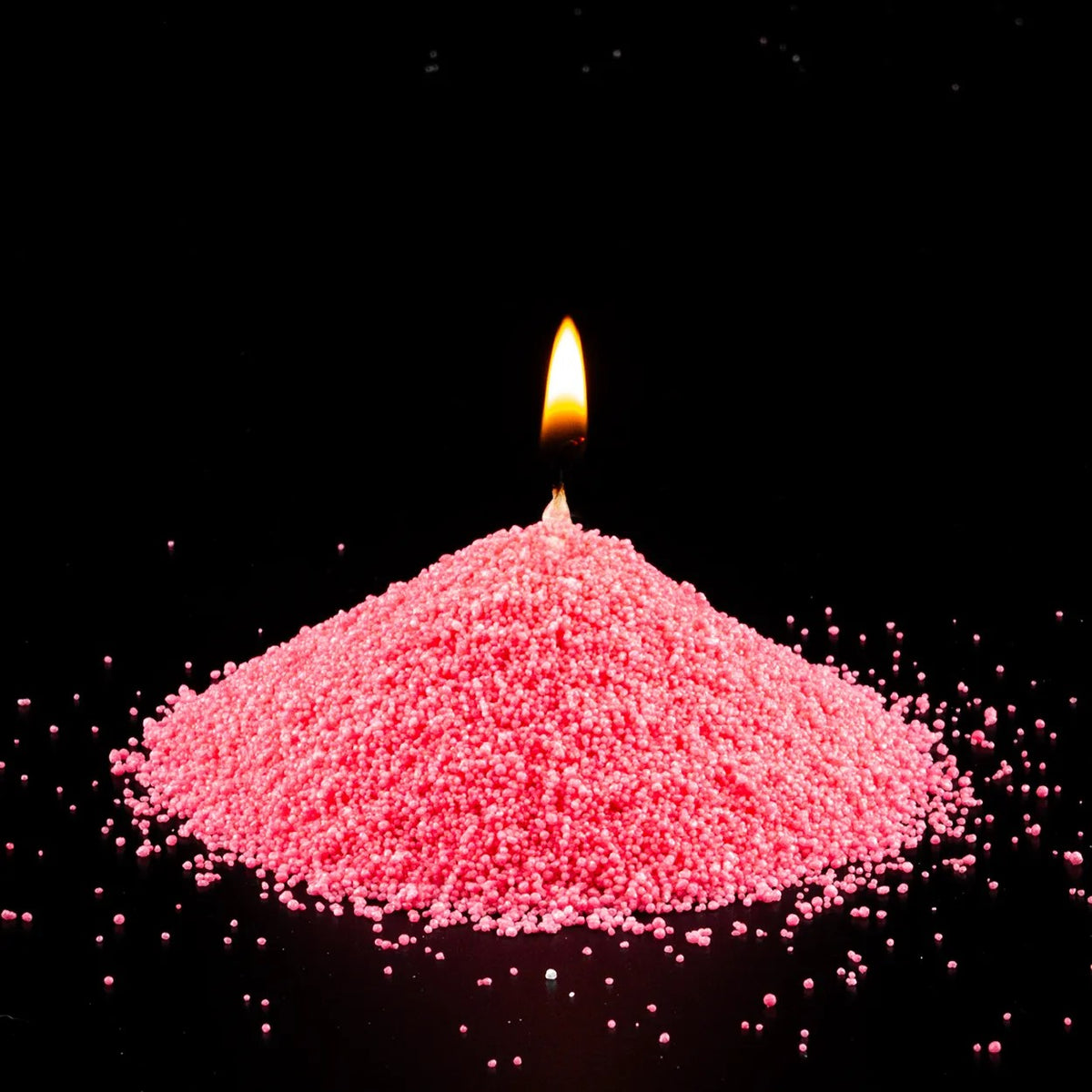Burning Blush Vintage pearled sand candle with a bright flame isolated on a dramatic black background