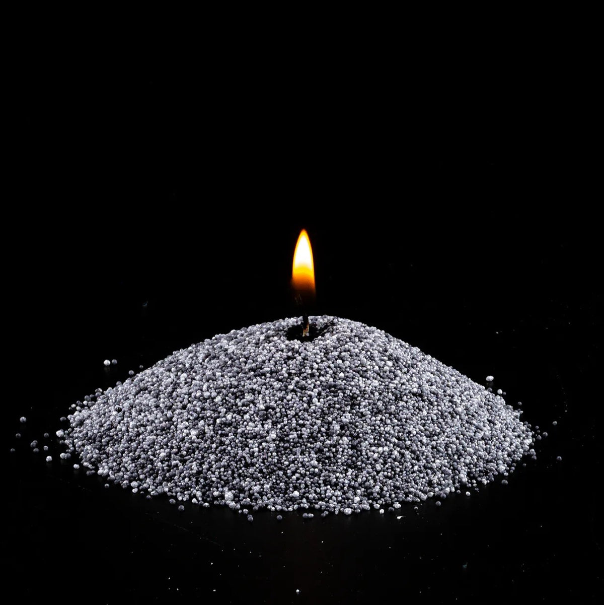 Burning Grey pearled sand candle with a bright flame isolated on a dramatic black background