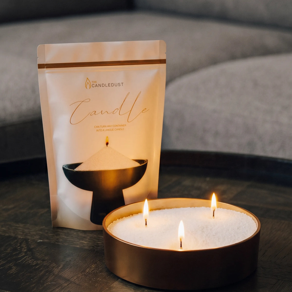 Lit Ivory pearled sand candle and pouch displayed on a decorative tray resting on a dark table