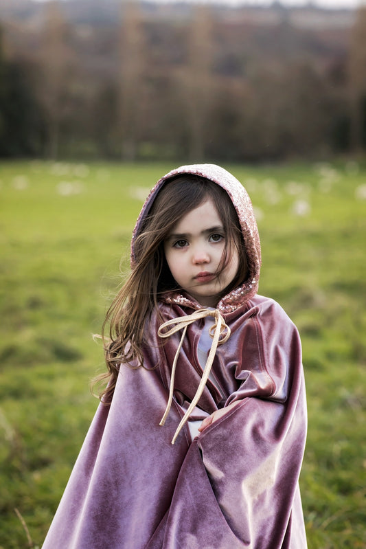 Outdoor magic: pearlescent velvet cape flowing against a backdrop of blue sky and trees
