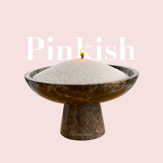 Pinkish text on a matching soft pinkish background with a glass vase full of unlit pearled candle sand in the foreground