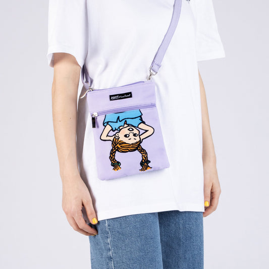 Person wearing the lilac Pippi Longstocking crossbody passport bag in a casual travel setting