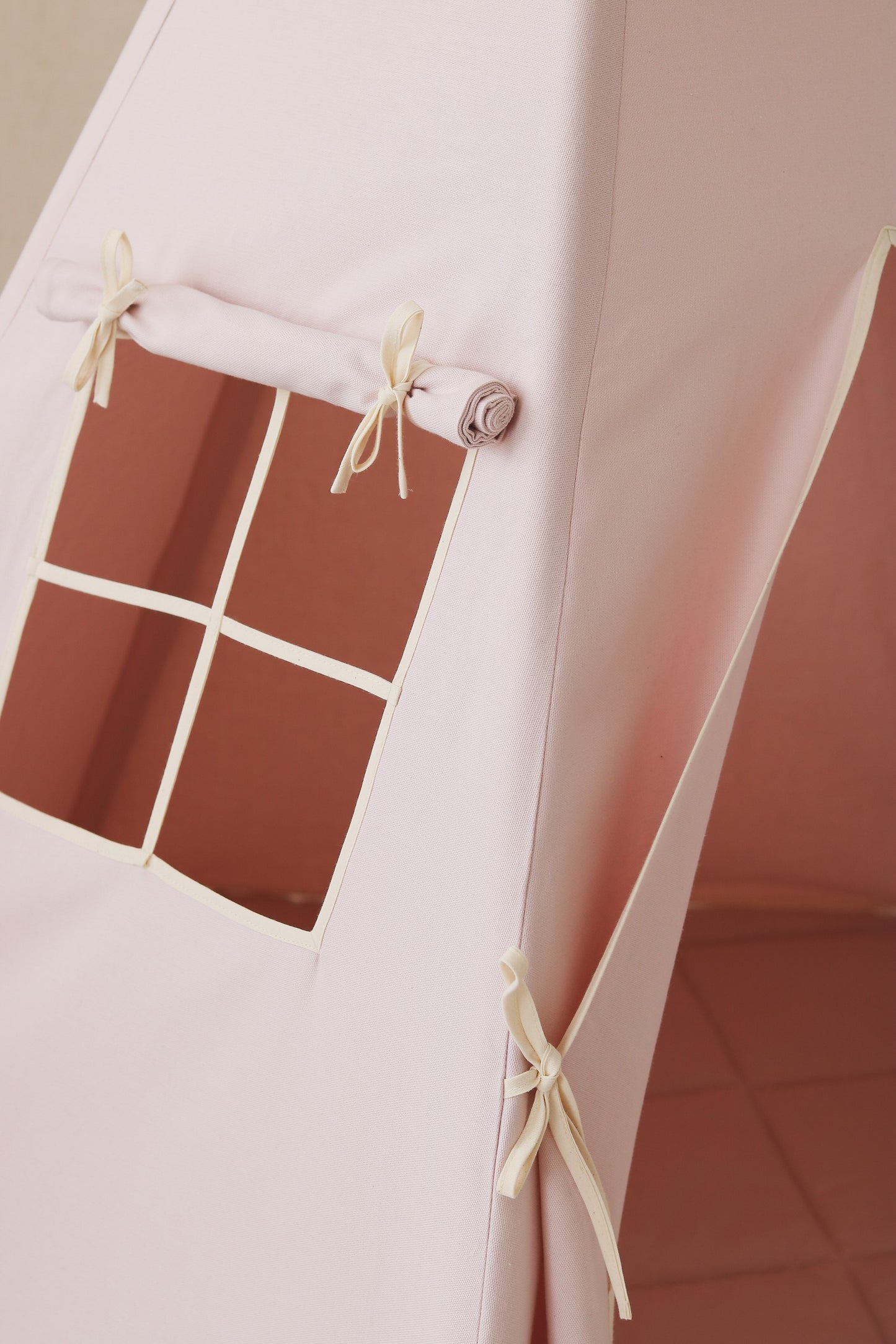 Nursery detail: close-up of the charming side window on a Moi Mili Pink Teepee Tent, letting soft natural light into the dusty pink play space
