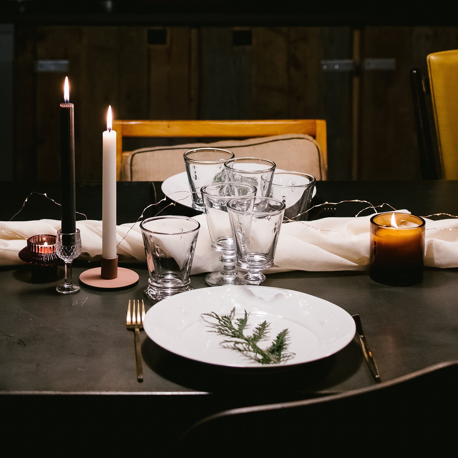 An intimate photograph of La Rochere Bee glasses arranged on a candlelit dinner table, with the warm glow of the candles highlighting the glass pattern.