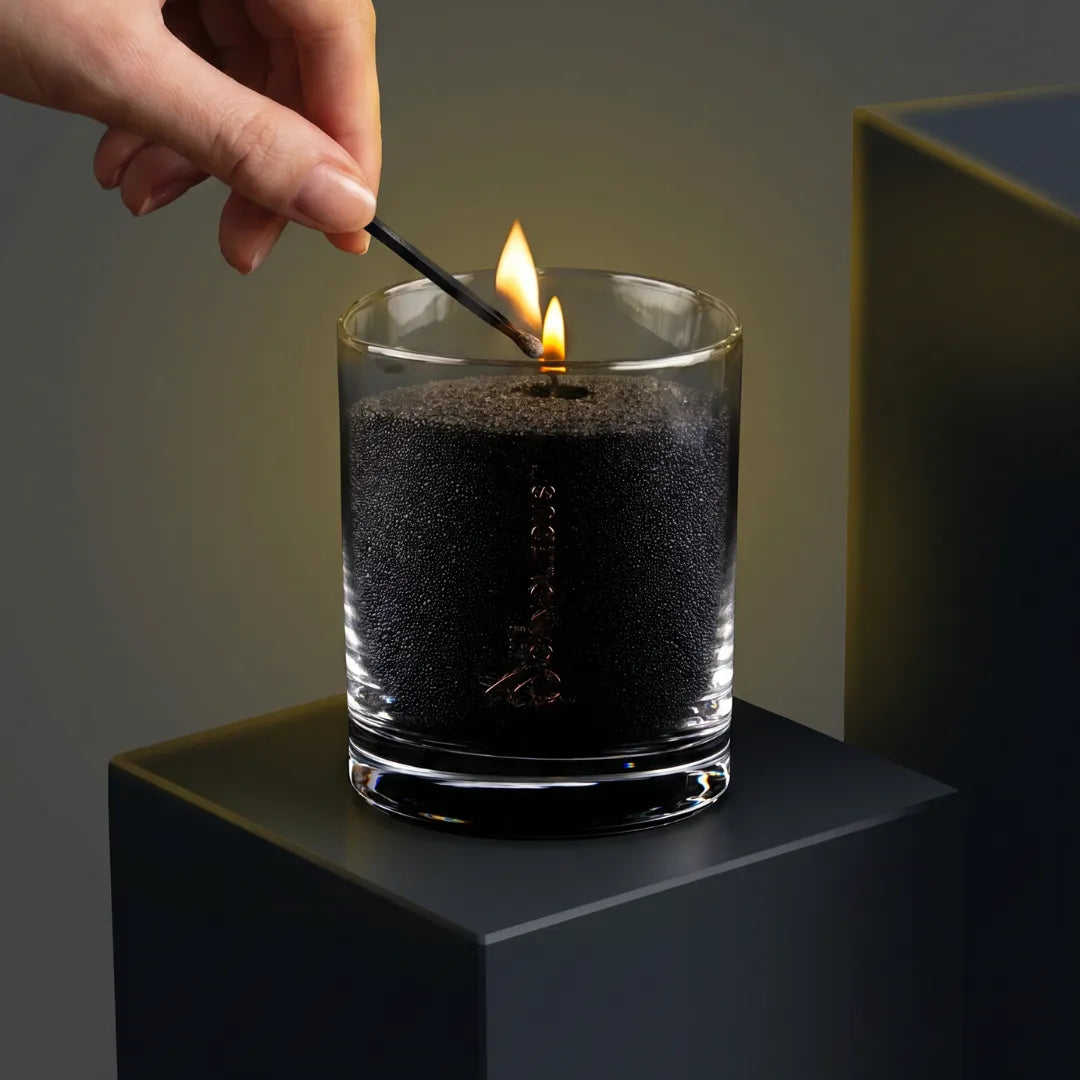 Close-up of a woman's hand lighting the cotton wick of a Black unscented pearled sand candle in glass