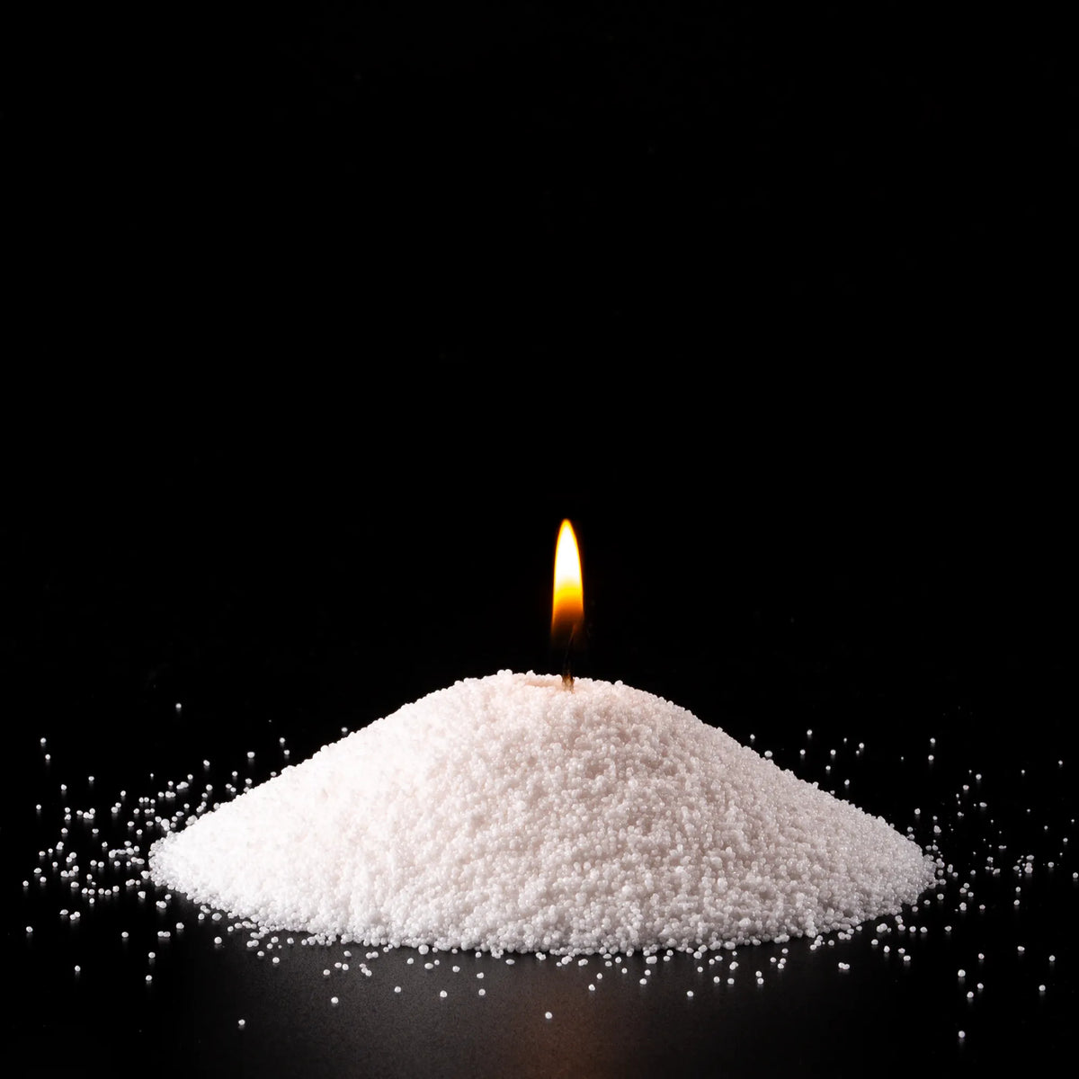 Burning Breeze pearled sand candle with a bright flame isolated on a dramatic black background