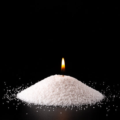 Burning Breeze pearled sand candle with a bright flame isolated on a dramatic black background