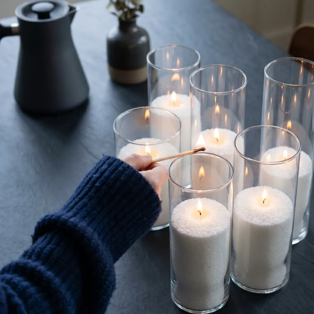 Close-up of a woman's hand lighting the cotton wick of a Breeze pearled sand candle
