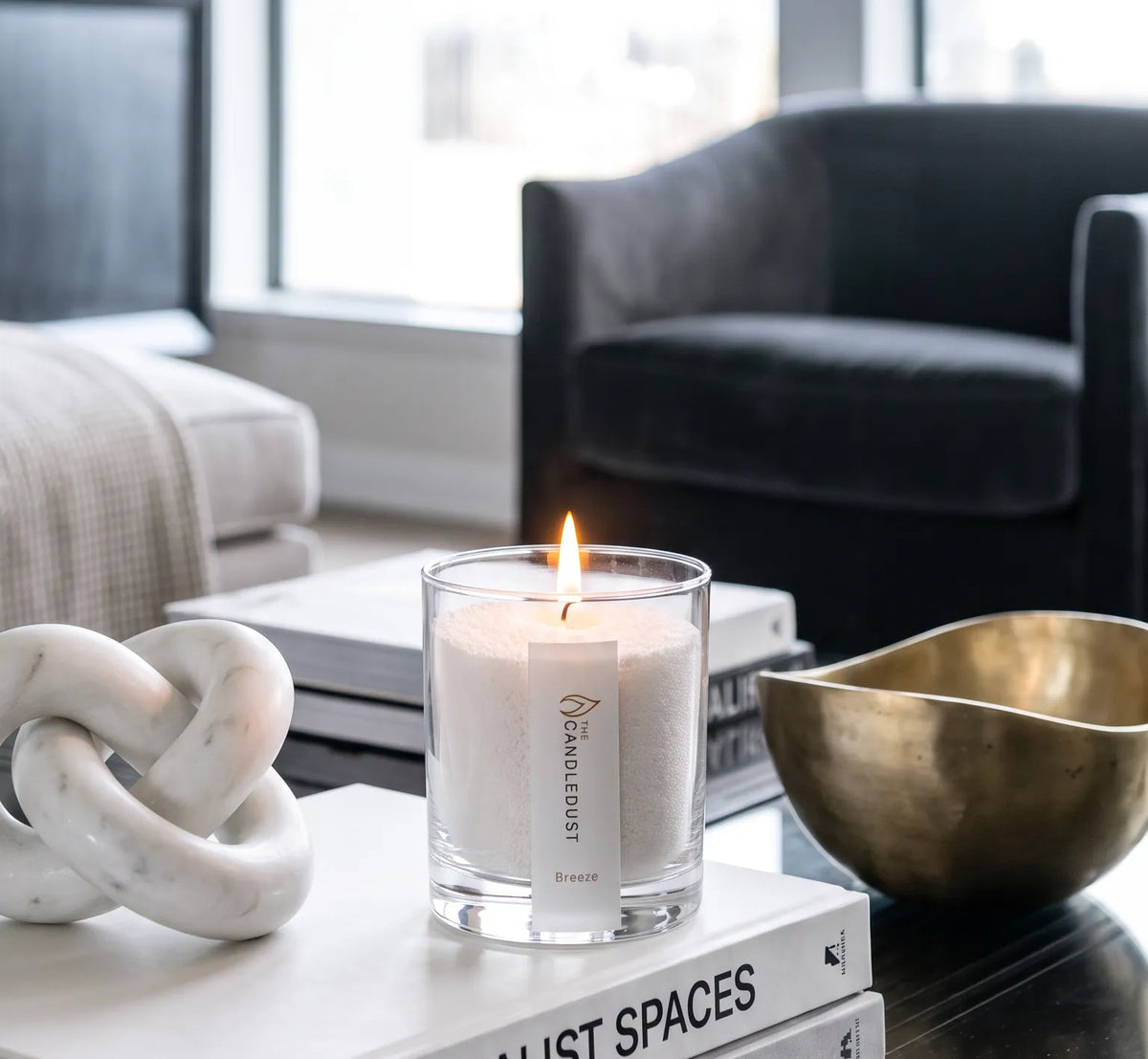 Lit Breeze scented pearled glass candle displayed on stacked books