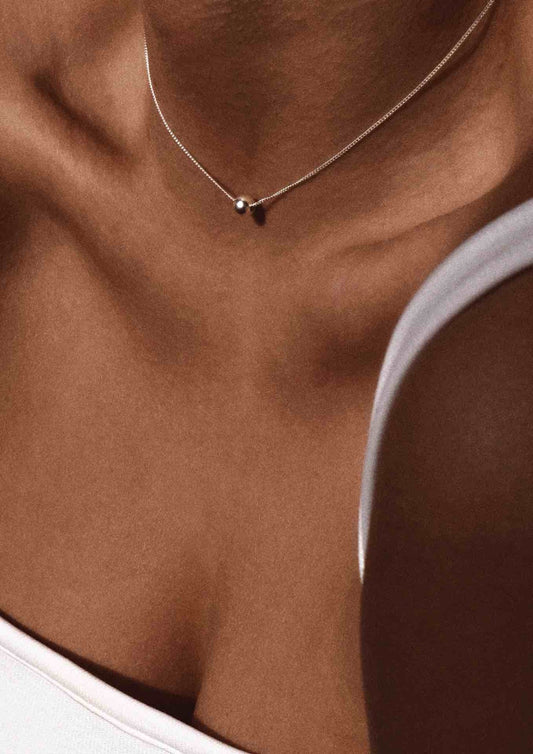 Close-up of a woman wearing the minimalist silver Bubble Necklace on her collarbone.