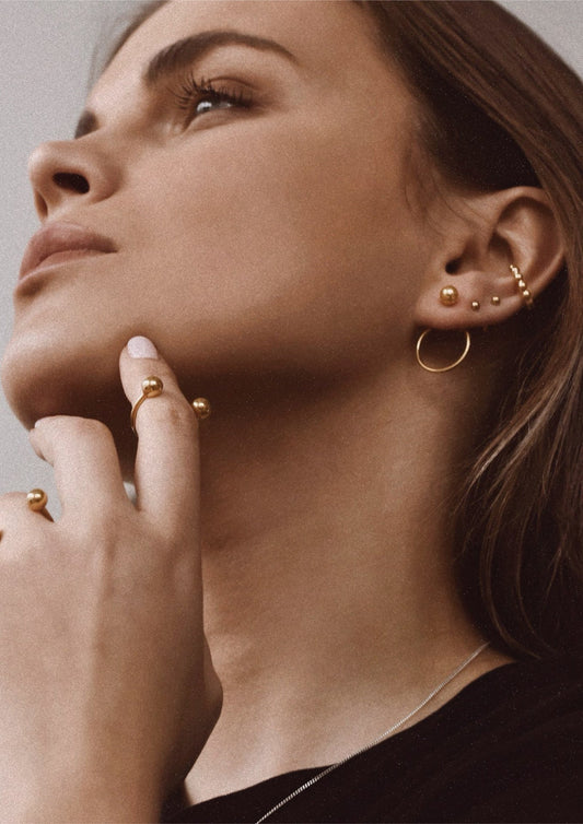 A stylish woman highlighting the handmade gold Chord Earrings in her ears.