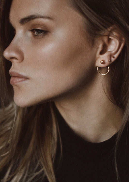 Side profile of a model showing the gold Chord Earrings in an elegant ear stack.