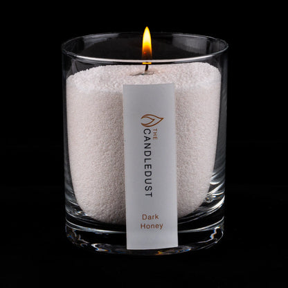 Lit Candledust Dark Honey scented pearled candle in a 160g glass jar on a black background