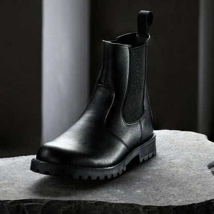 Black leather boot on a gray surface with a dark background