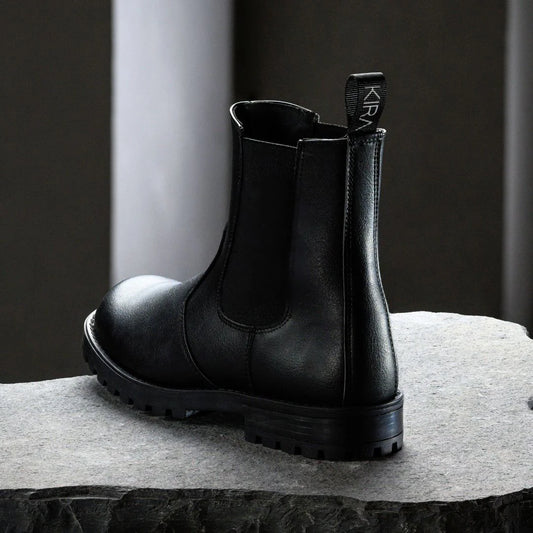Black leather boot on a gray surface with a dark background