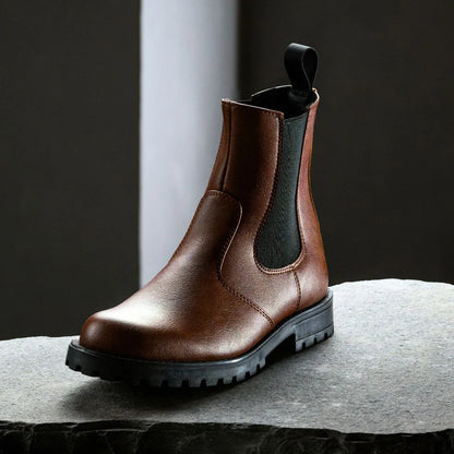 Brown leather boot with black sole on a dark background