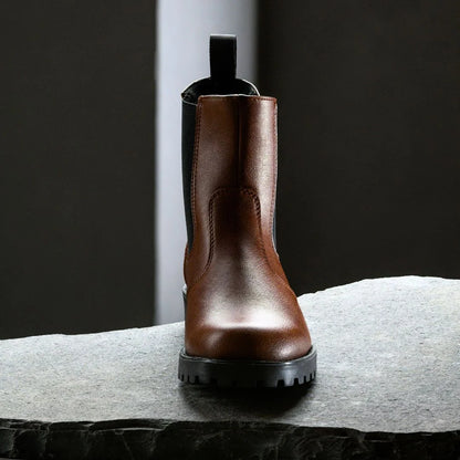 Brown leather boot on a textured surface with a dark background