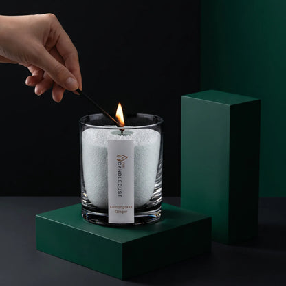 Close-up of a woman's hand lighting the cotton wick of a Lemongrass Ginger scented pearled sand candle in glass