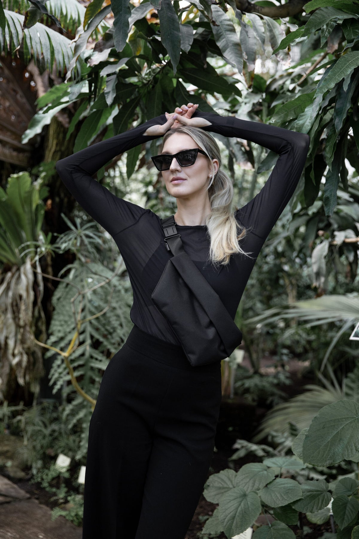 Woman wearing OSLO Cross Body Bag outdoor near some green plants