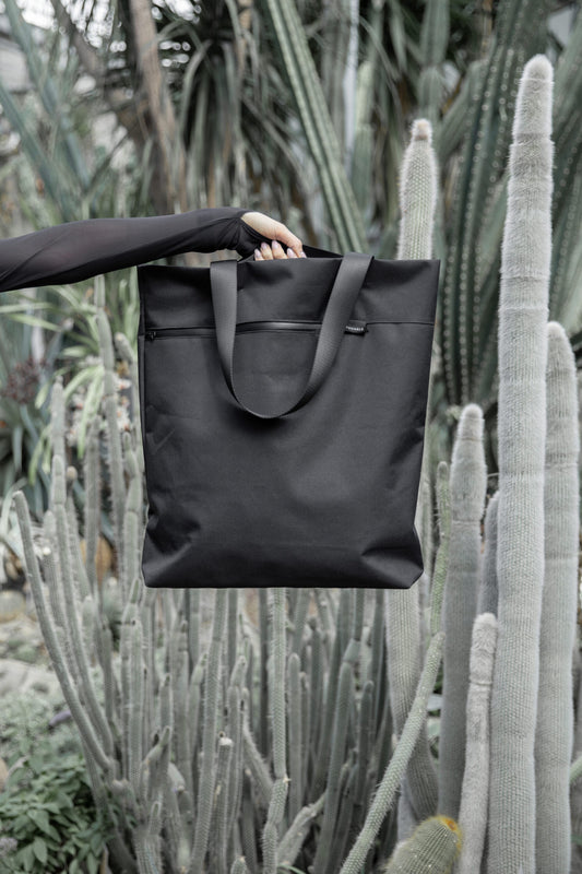 Model standing outside carrying VIK Large Tote Bag in one hand, sustainable fashion