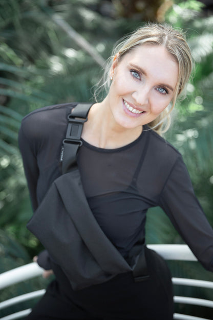 Smiling female model wearing OSLO Crossbody Bag in recycled felt, minimalist eco-friendly style