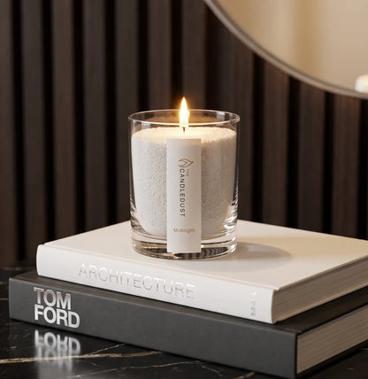 Lit Midnight scented pearled glass candle resting on stacked books