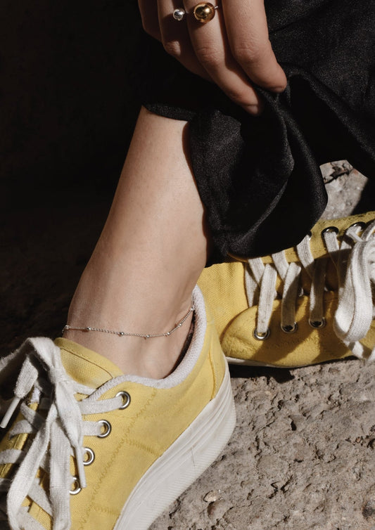 Close-up of a woman's ankle gracefully wearing the silver Mini Bubble Anklet.
