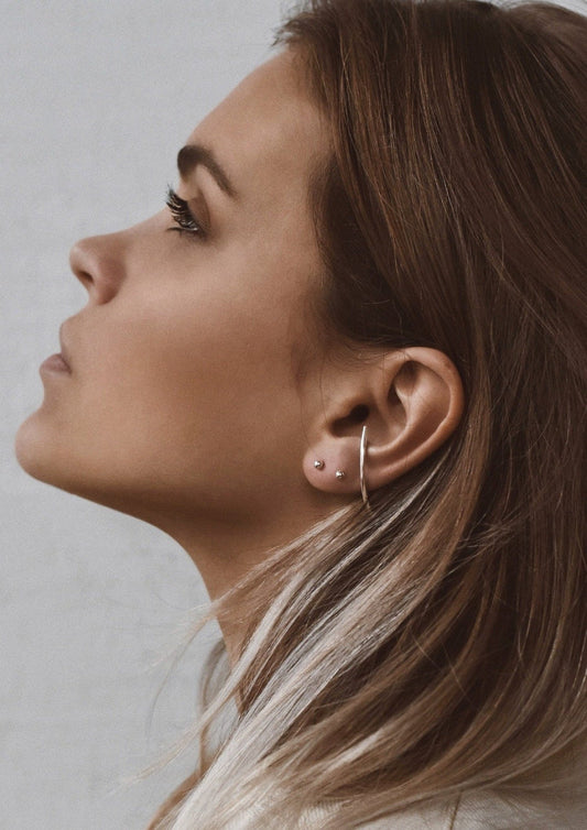 A woman's profile highlighting the handmade silver Radius Earrings.