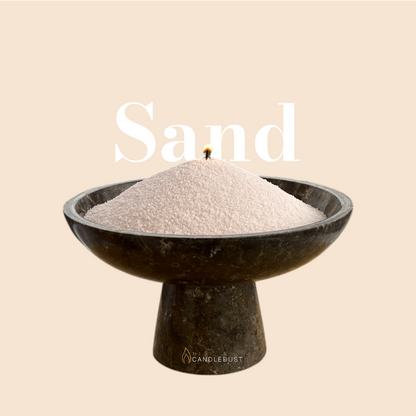Sand text on a matching warm sand background with a glass vase full of unlit pearled candle sand in the foreground