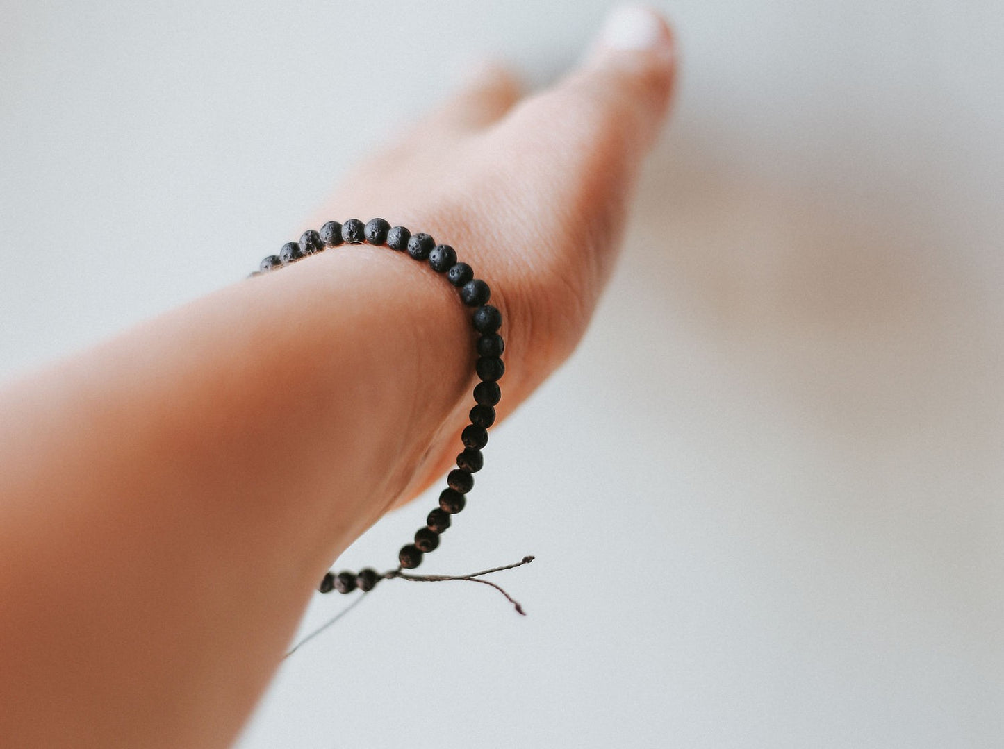 Worn Adjustable minimalist bracelet with 4mm porous black lava beads on a durable cord