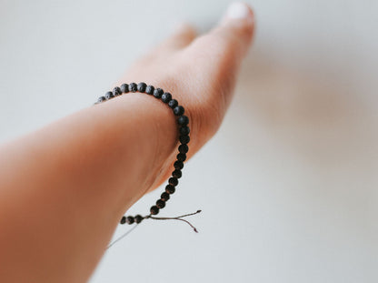 Worn Adjustable minimalist bracelet with 4mm porous black lava beads on a durable cord