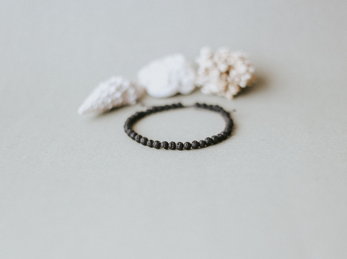 Adjustable minimalist bracelet with 4mm porous black lava beads on a durable cord