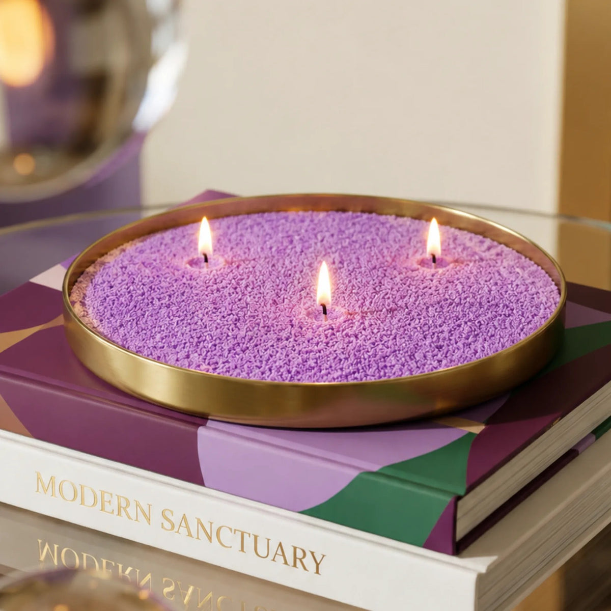 Lit Amethyst pearled sand candle displayed on a decorative tray resting on stacked books