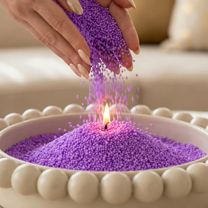 Woman pouring Amethyst pearled candle sand into an elegant tray with one already lit wick burning