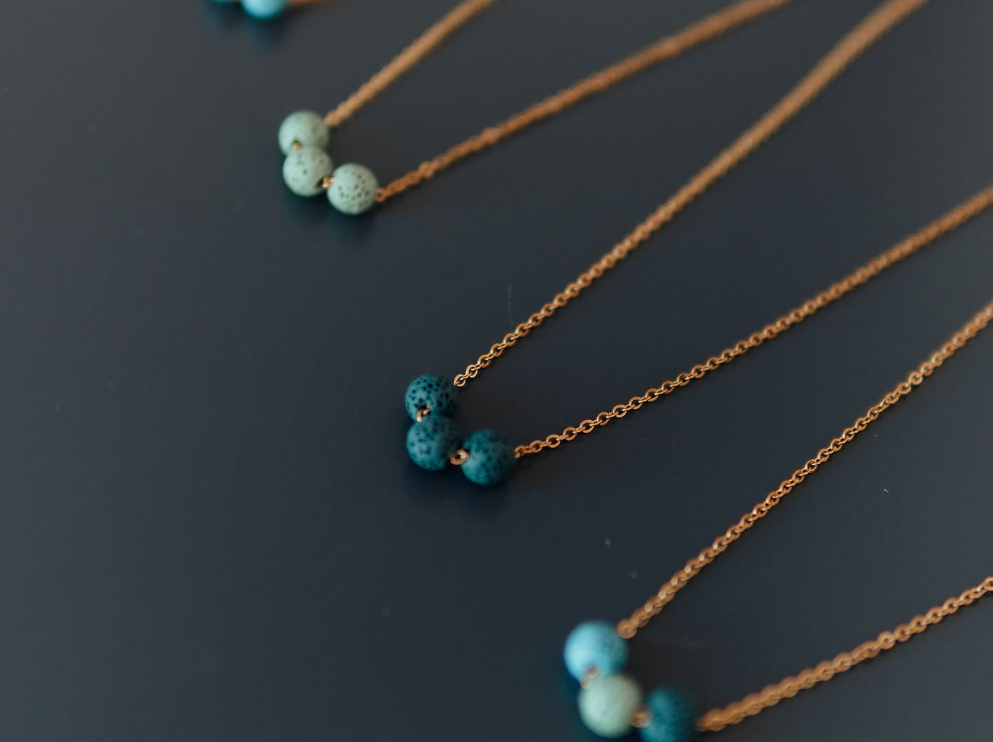 Perspective view of the minimalist lava stone diffuser necklace showing bead size and chain length