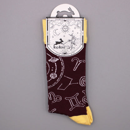 Folded Hop Hare Zodiac bamboo socks with original paper sleeve packaging on a smooth gray background