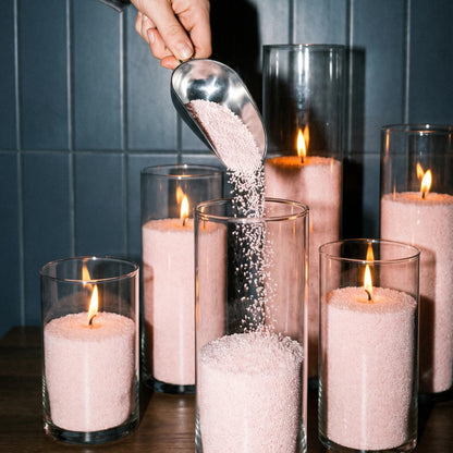 Other view of Woman filling decorative glass candle holders with Baby Pink natural pearled candle sand
