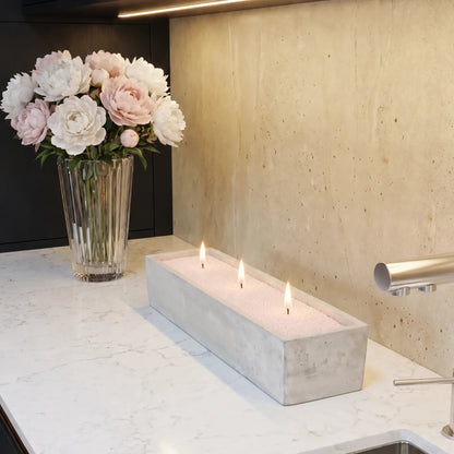 Elegant marble vase filled with Baby Pink pearled candle sand and lit cotton wicks resting on a refined marble countertop