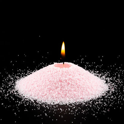 Burning Baby Pink pearled sand candle with a bright flame isolated on a dramatic black background