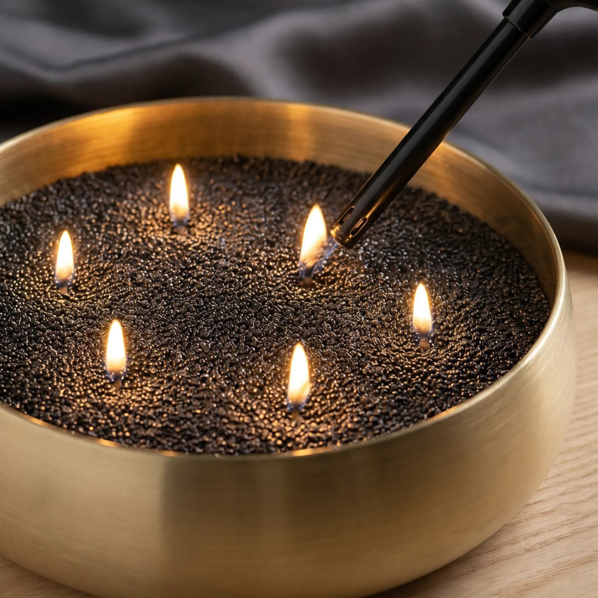 Close-up of a hand lighting the cotton wicks of a Black pearled sand candle