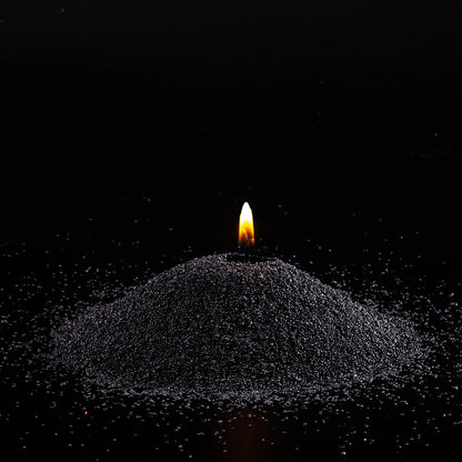 Burning Black Unscented pearled sand candle with a bright flame isolated on a dramatic black background