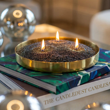 Lit Black pearled sand candle displayed on a decorative tray resting on stacked books